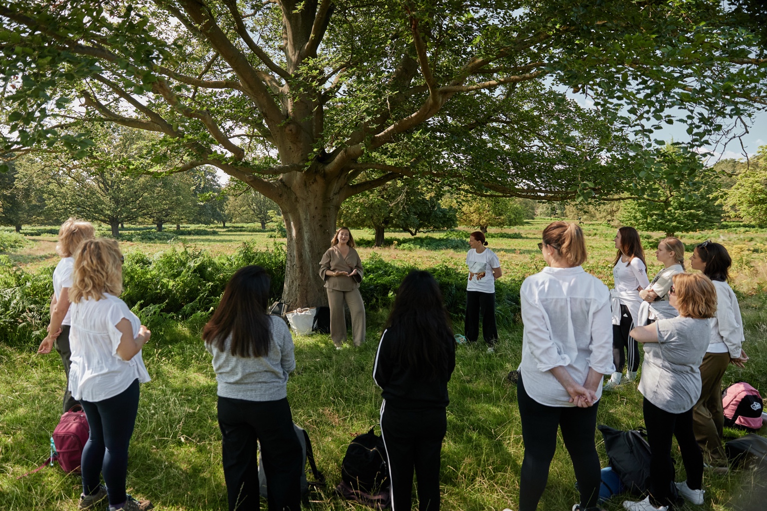 Linda guiding participants gathered beneath a large tree