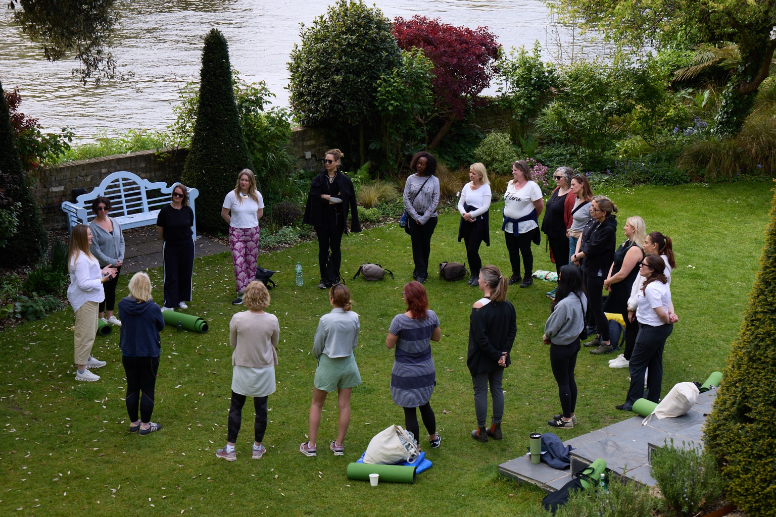 Linda guiding a group standing in a circle in riverside gardens